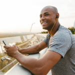 African american athlete man listening to the music and using mobile phone outdoors